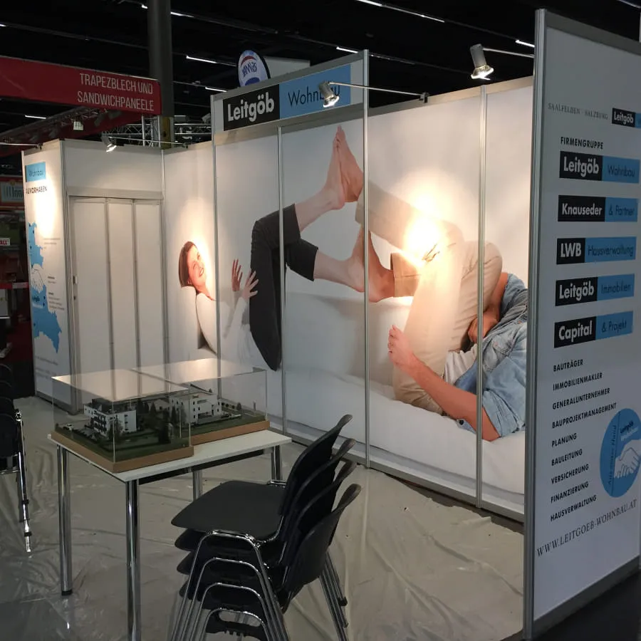 Messestand mit Bildern von Personen und Modell auf Tisch