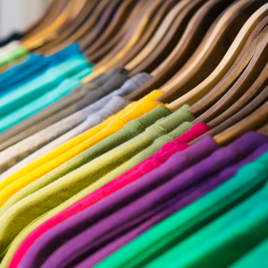 Bunte T-Shirts auf Holzkleiderbügeln arrangiert