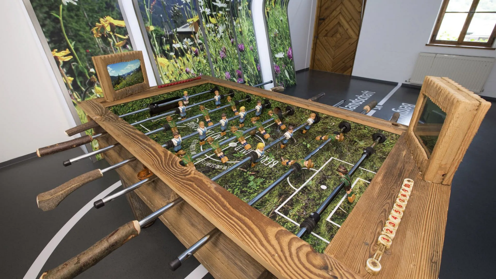 Holzfußballtisch in einem Raum mit Blumenwand
