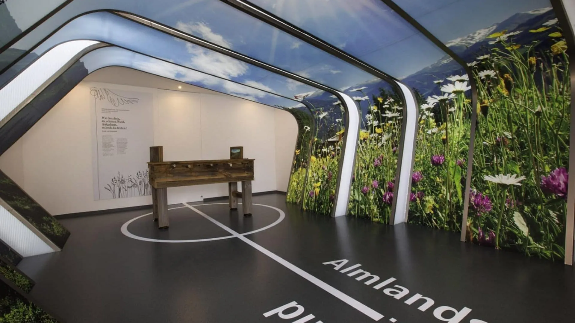 Moderne Ausstellung mit Blumenwand und Holzstapel in der Mitte