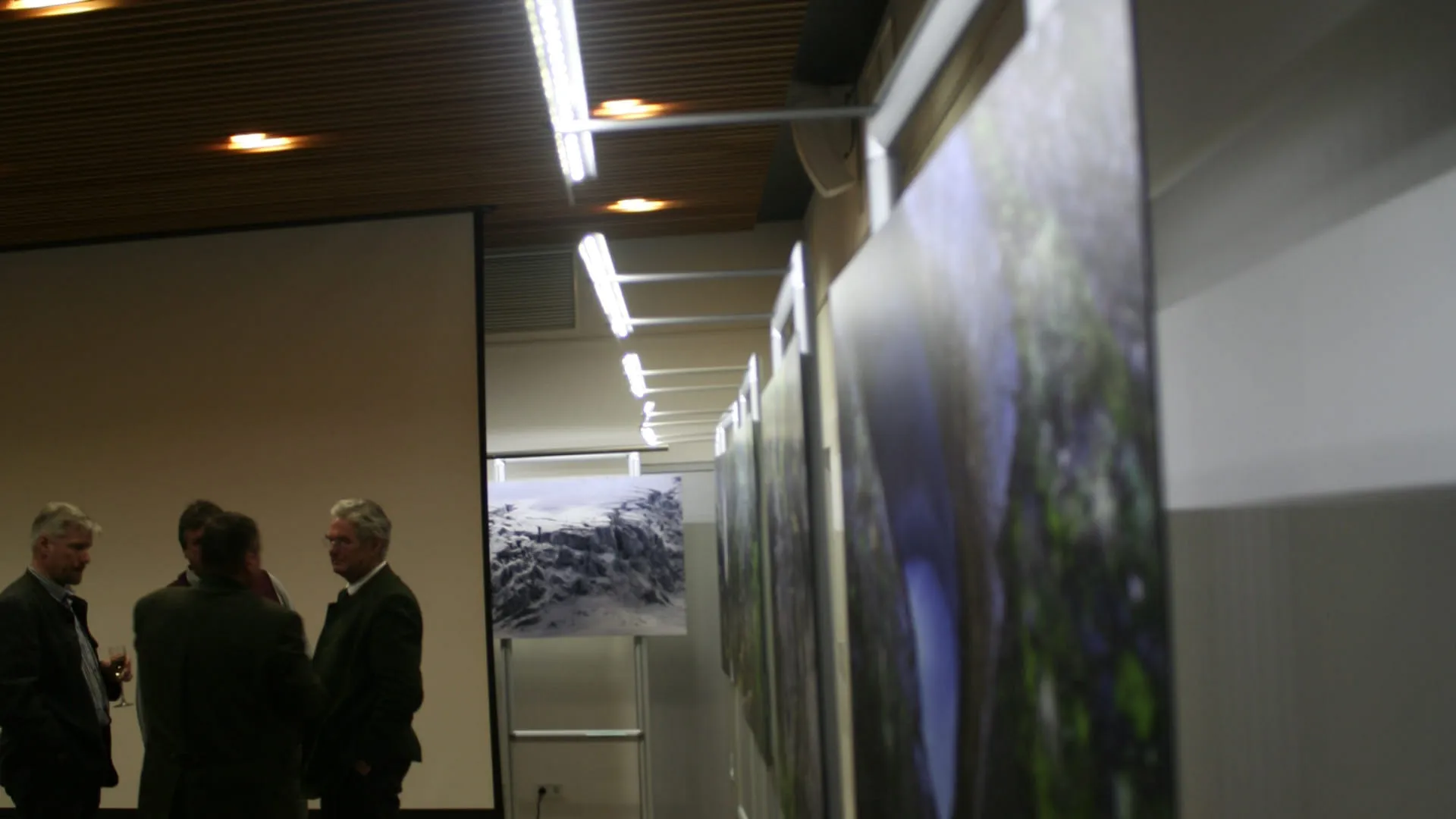 Besucher in einem Ausstellungsraum mit Bildern und Lichtinstallationen