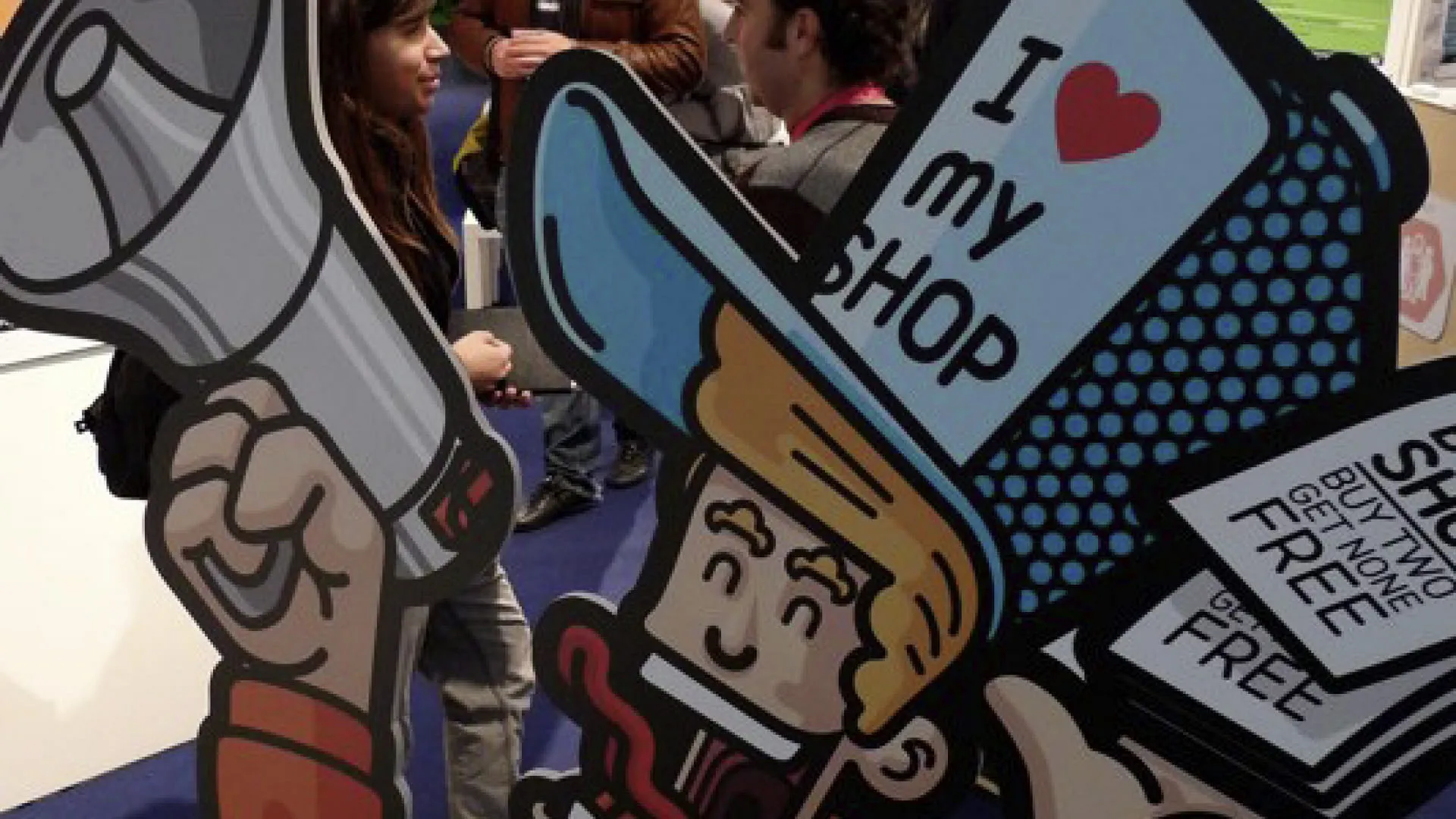 Personen stehen neben einem großen Werbeschild für einen Shop.