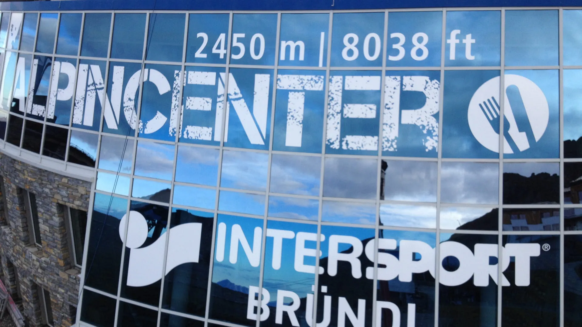 Spiegelung des ALPINCENTER-Schilds in den Bergen