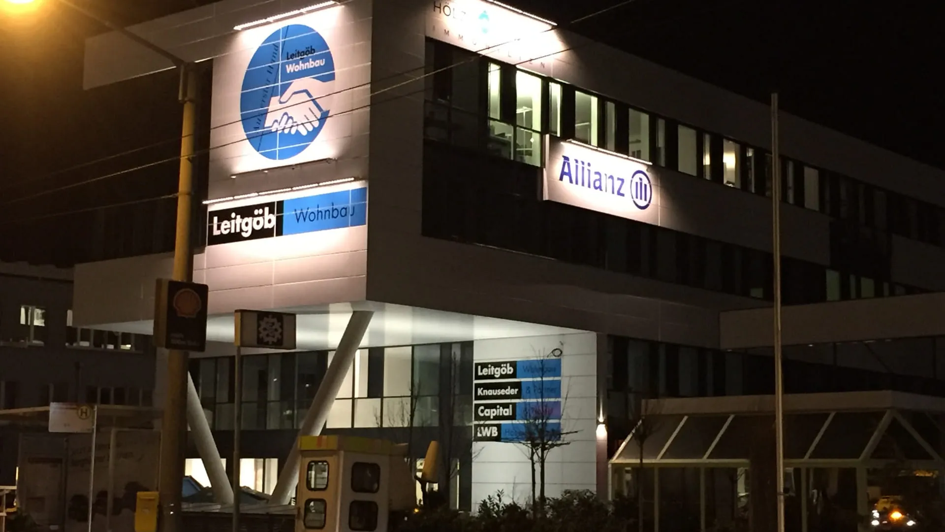 Moderne Bürogebäude mit Allianz und Leitgeb Logos bei Nacht