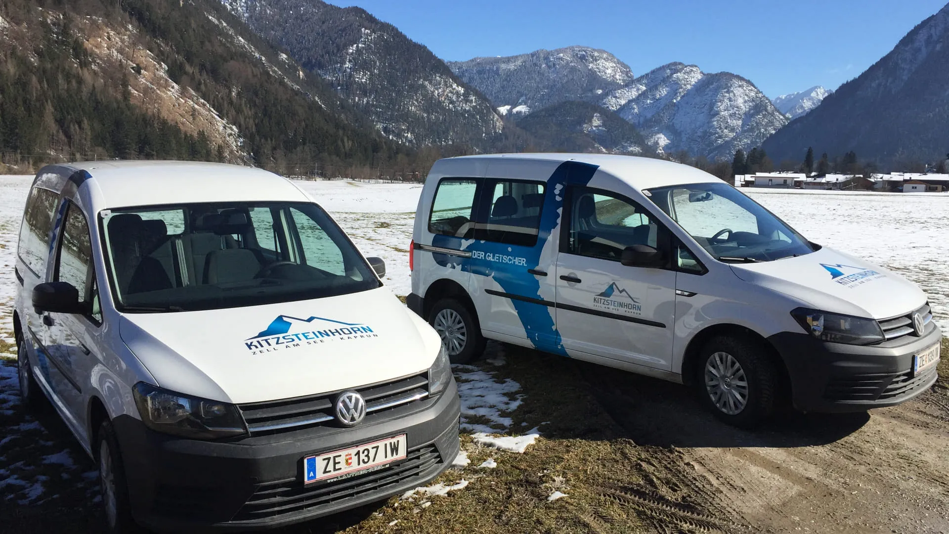 Zwei Lieferwagen in einer gebirgigen Landschaft mit Schnee.
