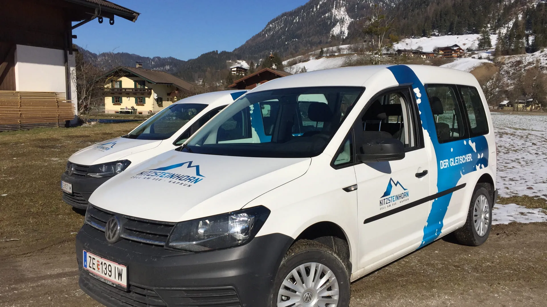 Weißer VW Transporter vor Berglandschaft und Schnee