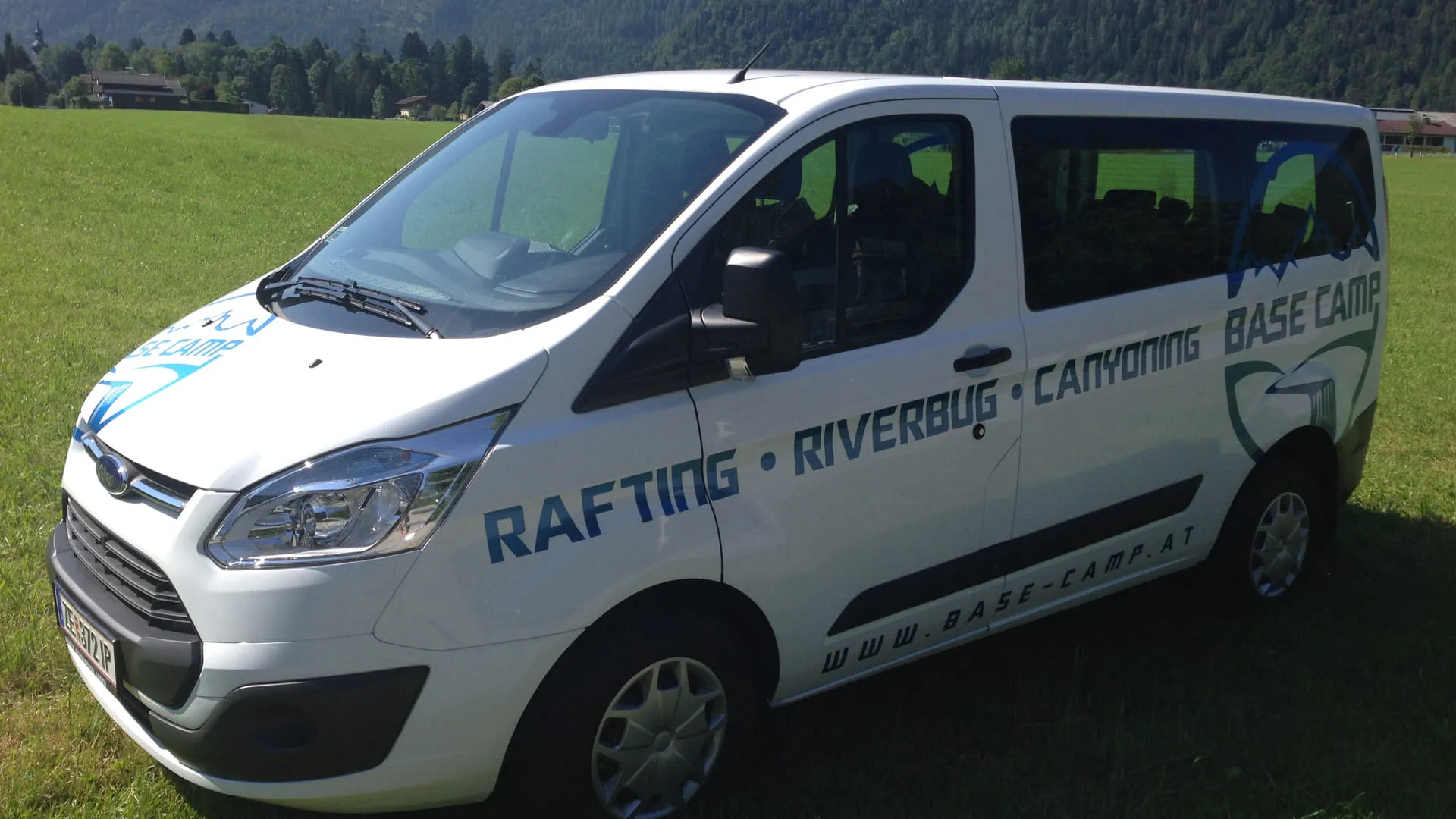 Weißer Van mit Aktivitätenbeschriftung auf einer Wiese