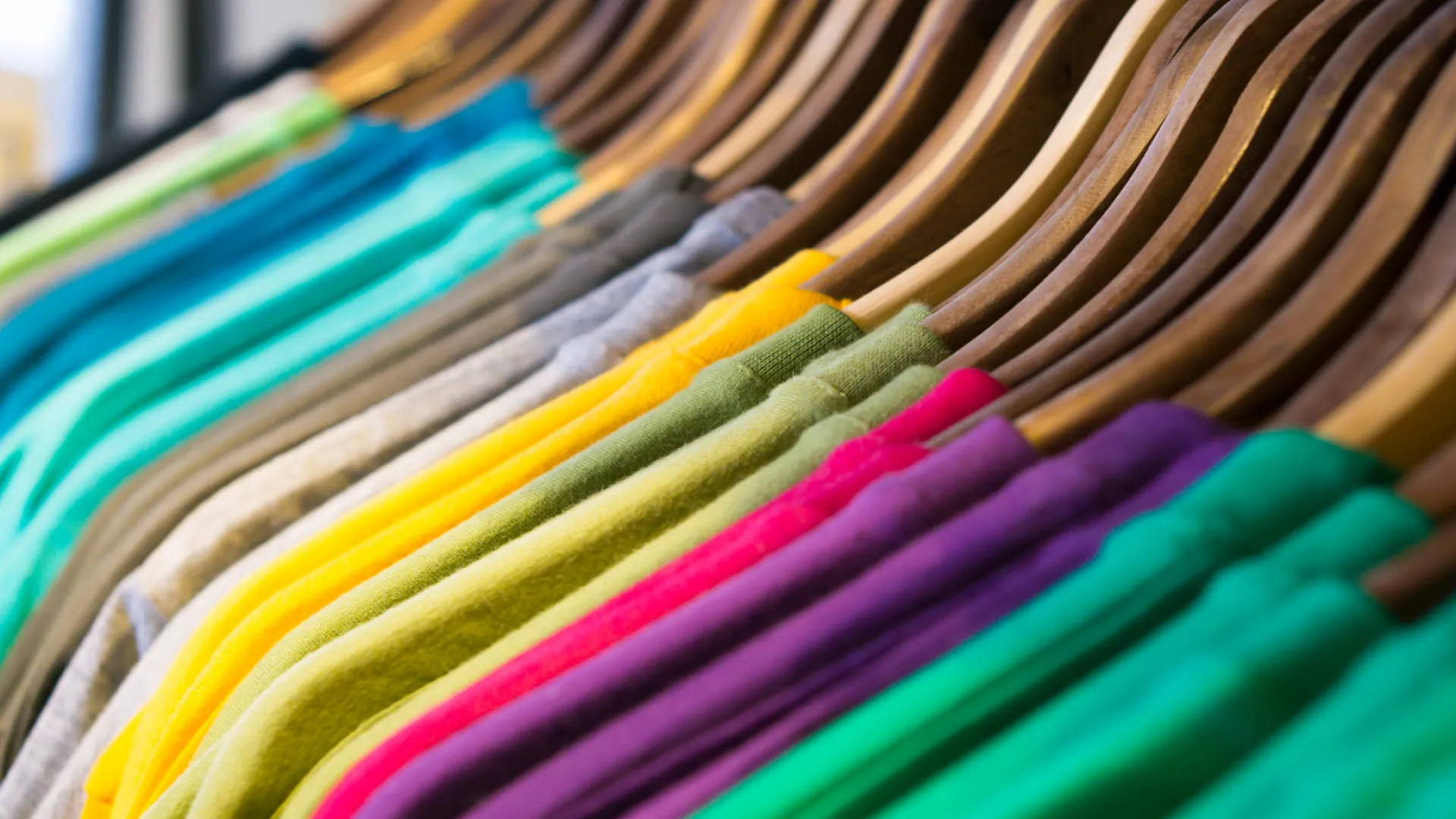 Bunte Shirts auf Holzkleiderbügeln angeordnet
