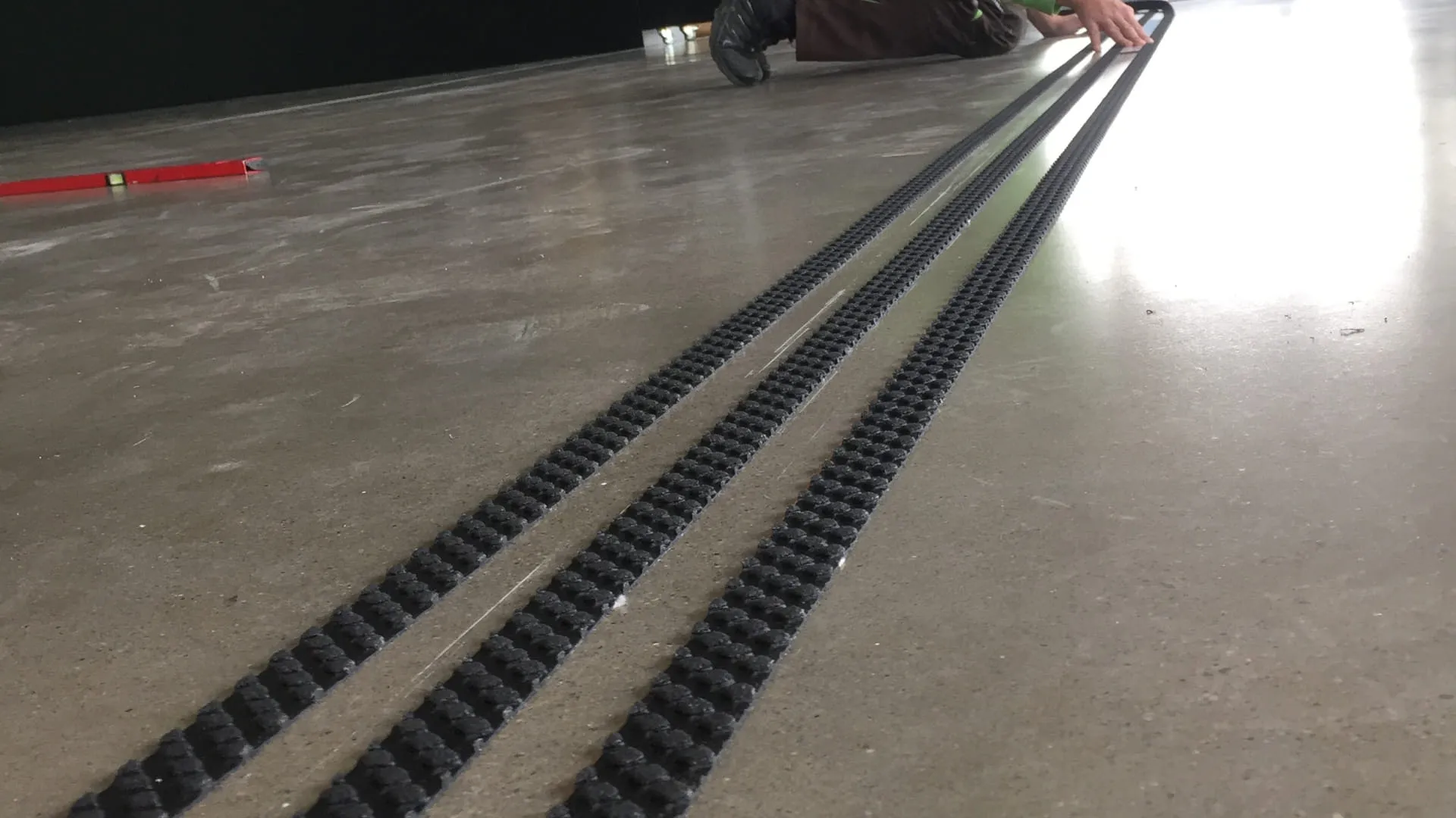 Mann verlegt schwarze Linien auf einem Betonboden