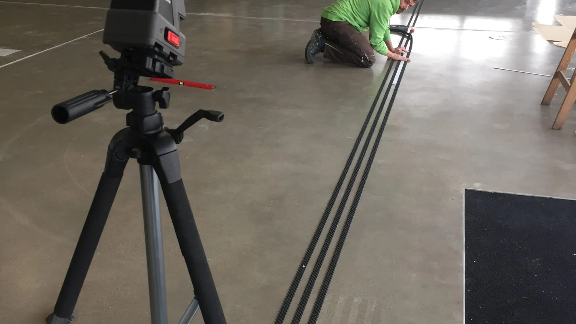 Person mit Lasergerät markiert Linien auf dem Boden