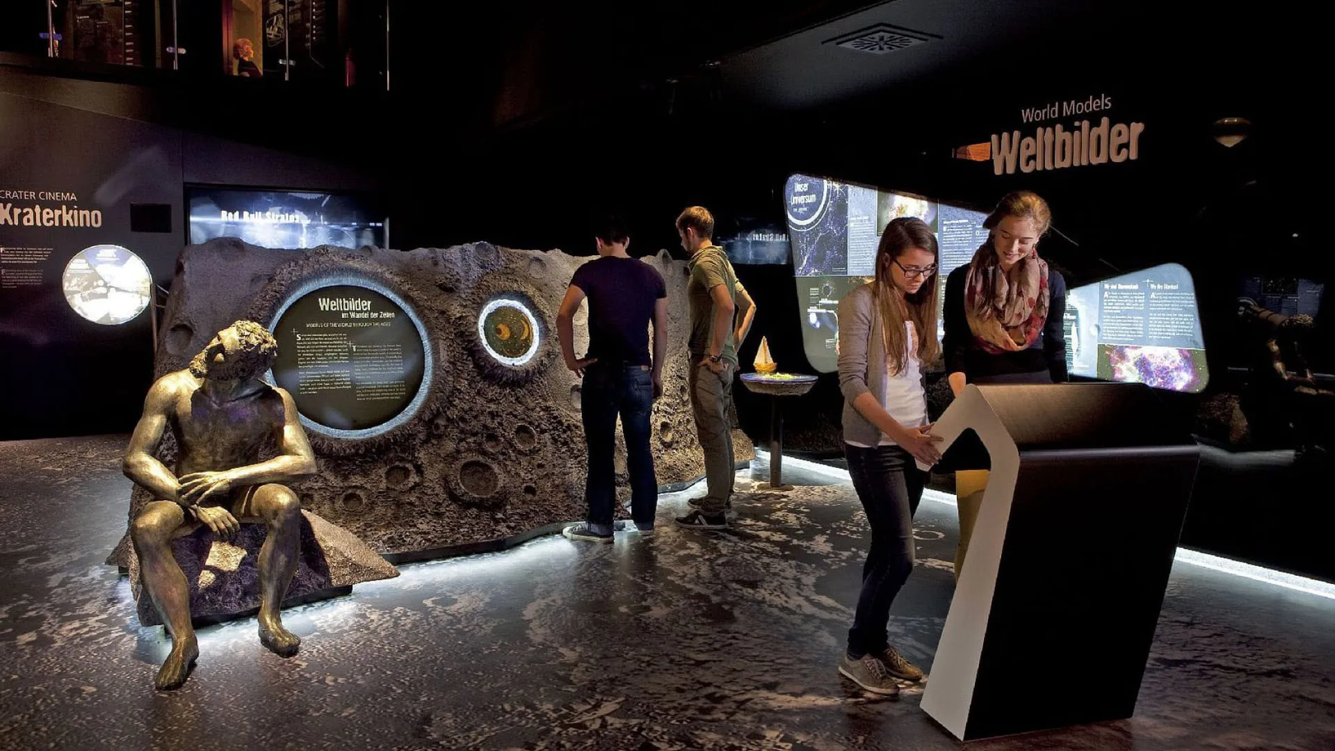 Interaktive Ausstellung mit Menschen und einem goldenen Statue.